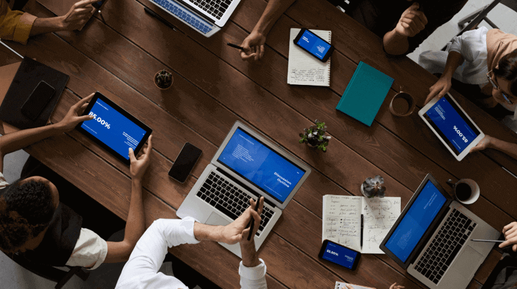 A team using laptops, tablets, and smartphones displaying a website, all collaborating.